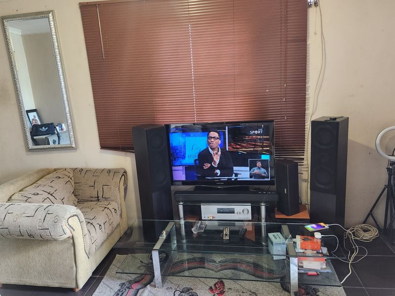A living room area featuring tiled flooring and venetian blinds, currently showing signs of wear on the wall surfaces.