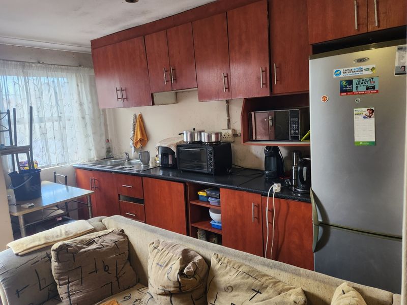 Open plan kitchen area featuring wood-look cabinetry and dark countertops, requiring cosmetic updates to improve the overall aesthetic and condition of the space.