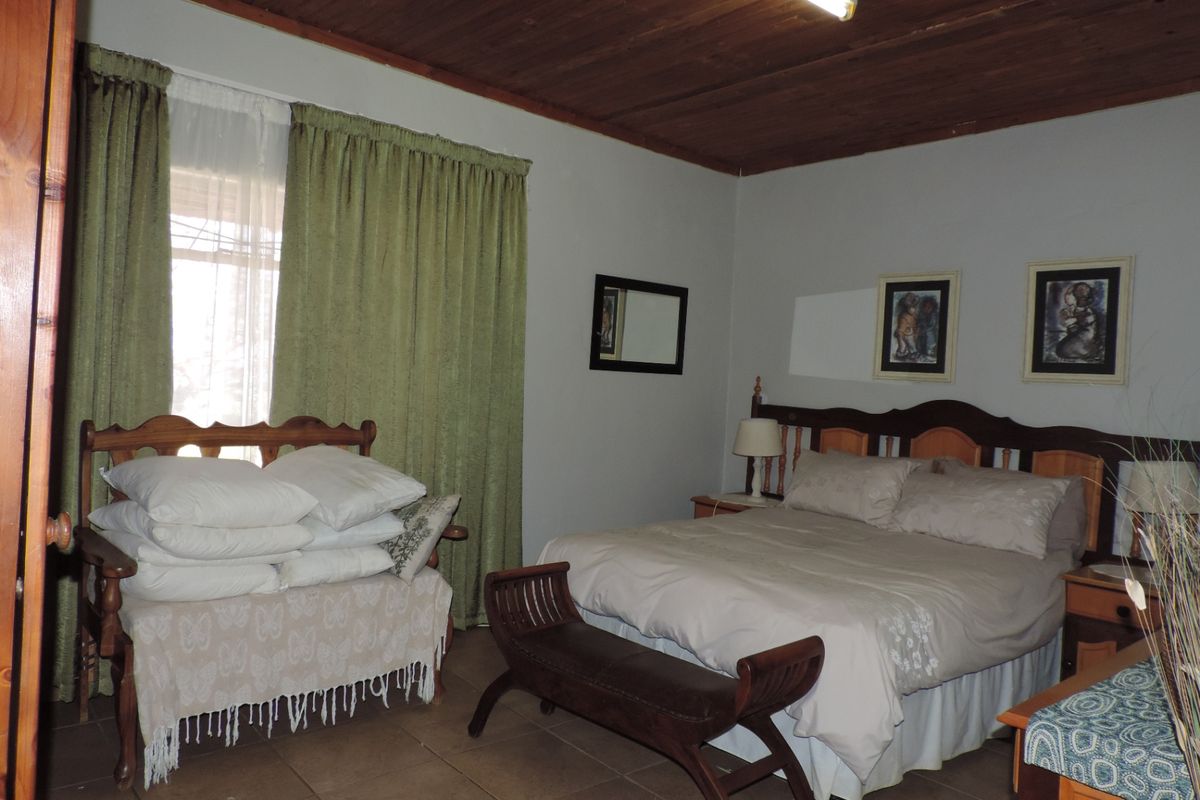 A bedroom featuring a timber ceiling, tiled flooring, and a neutral wall finish, offering a functional space with potential for cosmetic updates.