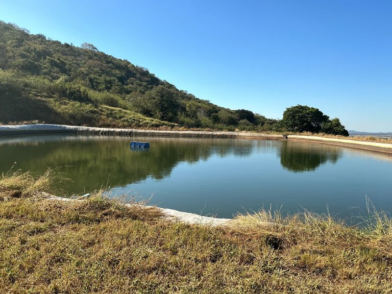 A large lined farm reservoir or dam situated on the property, surrounded by natural landscape and hillside terrain.