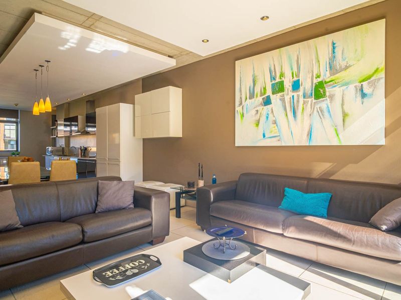 Spacious open-plan living and kitchen area featuring modern cabinetry, recessed lighting, and an exposed concrete ceiling design.