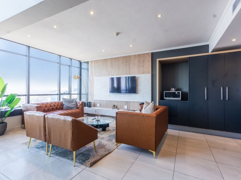 Modern living room featuring floor-to-ceiling windows, custom slatted wood and stone wall paneling, recessed lighting, and sleek built-in cabinetry.