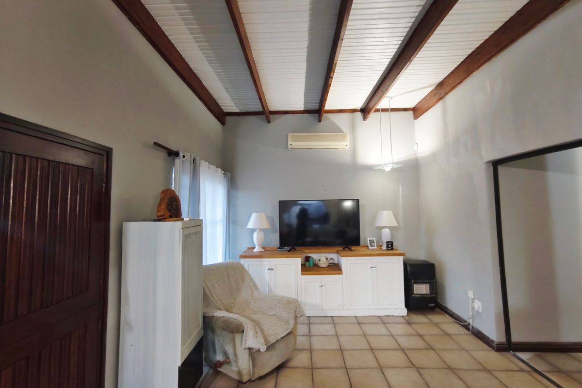 Living room featuring exposed timber ceiling beams, tiled flooring, and built-in cabinetry with a wall-mounted air conditioning unit.