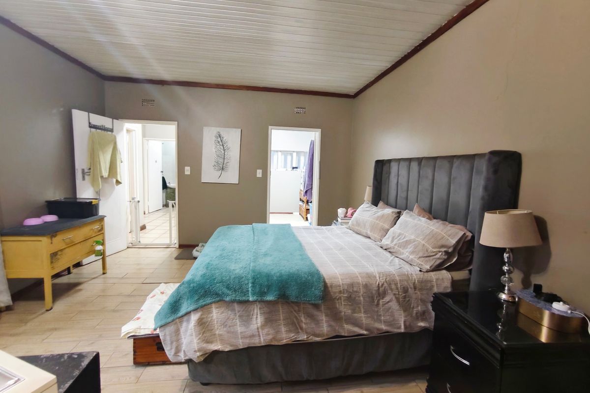 Spacious bedroom featuring timber-look tile flooring and a classic tongue and groove ceiling, providing a neutral foundation for personal styling.