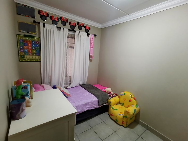 A standard bedroom featuring tiled flooring and crown molding, currently utilized as a child's room.