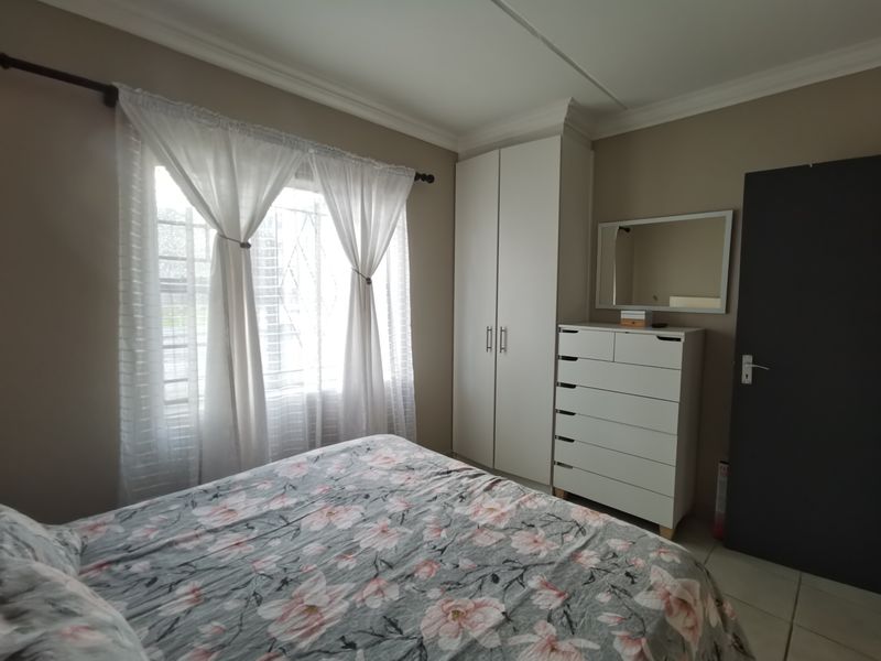 A well-maintained bedroom featuring neutral wall tones, tiled flooring, decorative cornice, and a functional built-in wardrobe.
