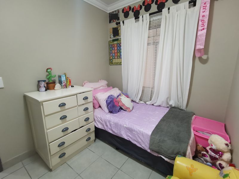 A functional bedroom featuring tiled flooring and neutral wall finishes, suitable for a child's room.