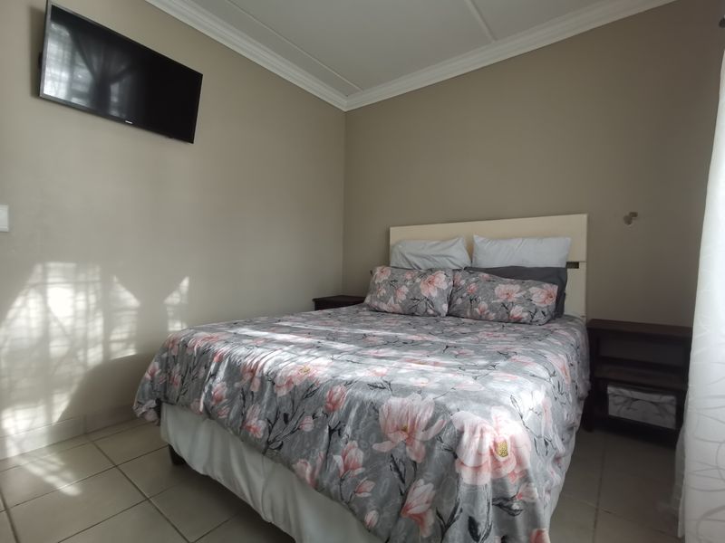 A bedroom featuring tiled flooring and crown molding, providing a functional space with neutral wall tones.