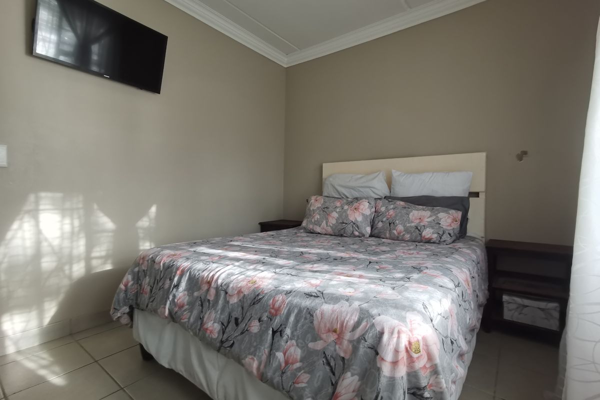 A bedroom featuring tiled flooring and crown molding, providing a functional space with neutral wall tones.