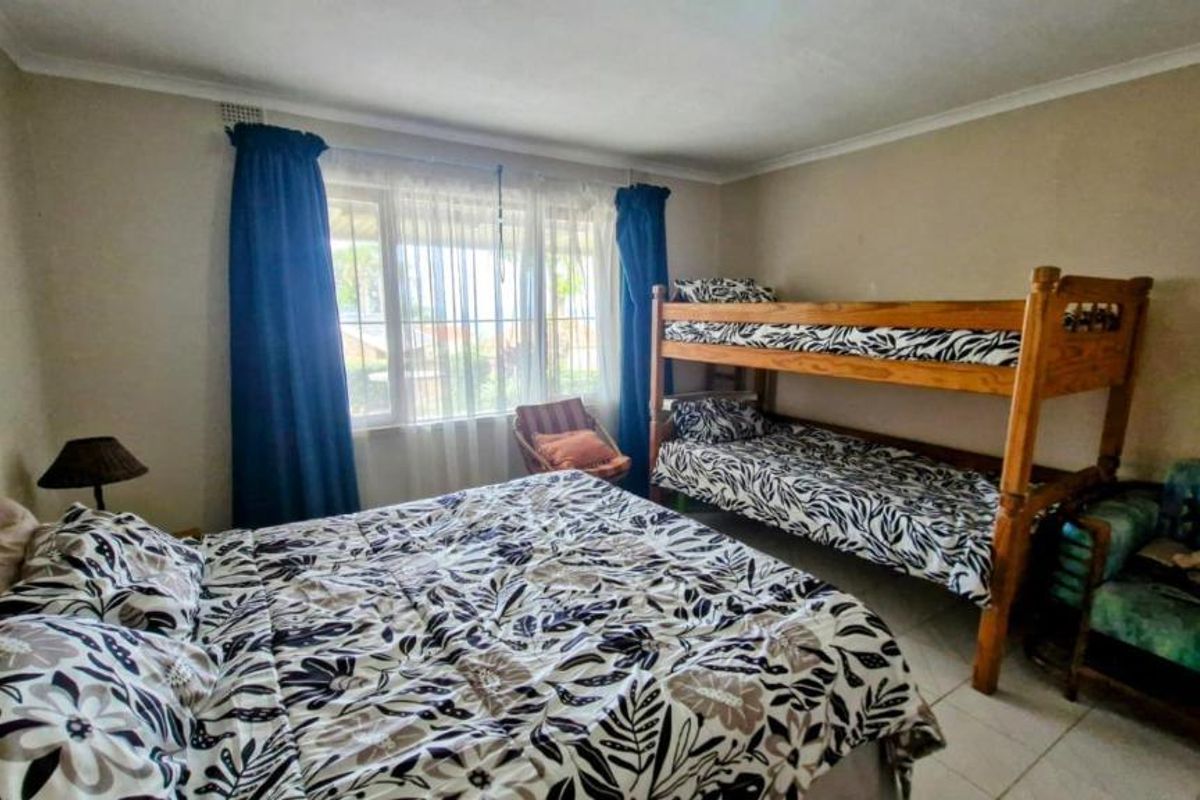 A functional bedroom featuring tiled flooring, cornicing, and security bars on the window, providing a practical space for sleeping arrangements.