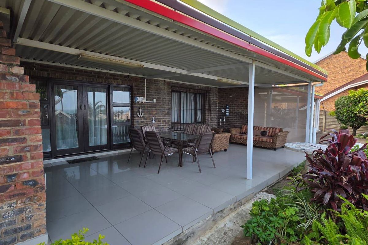A spacious covered patio featuring tiled flooring, exposed brick walls, and direct access to the interior through large sliding glass doors.