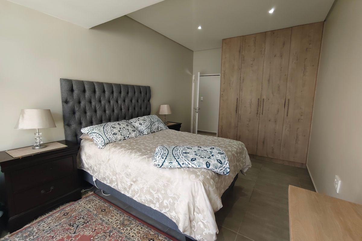 A well-maintained bedroom featuring neutral wall tones, tiled flooring, and ample built-in cupboard storage with modern recessed lighting.