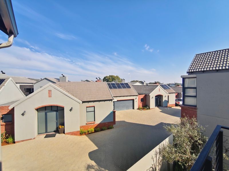 Elevated view of a modern townhouse complex featuring paved driveways, tiled roofs, and integrated solar panel installations.