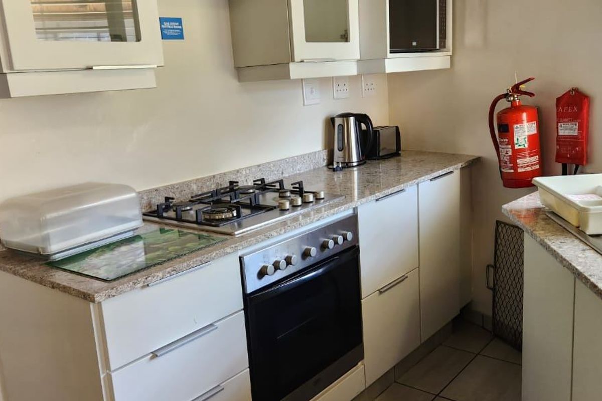 A functional kitchen featuring granite countertops, white cabinetry, a gas hob, and a built-in oven, providing a clean and practical cooking space.