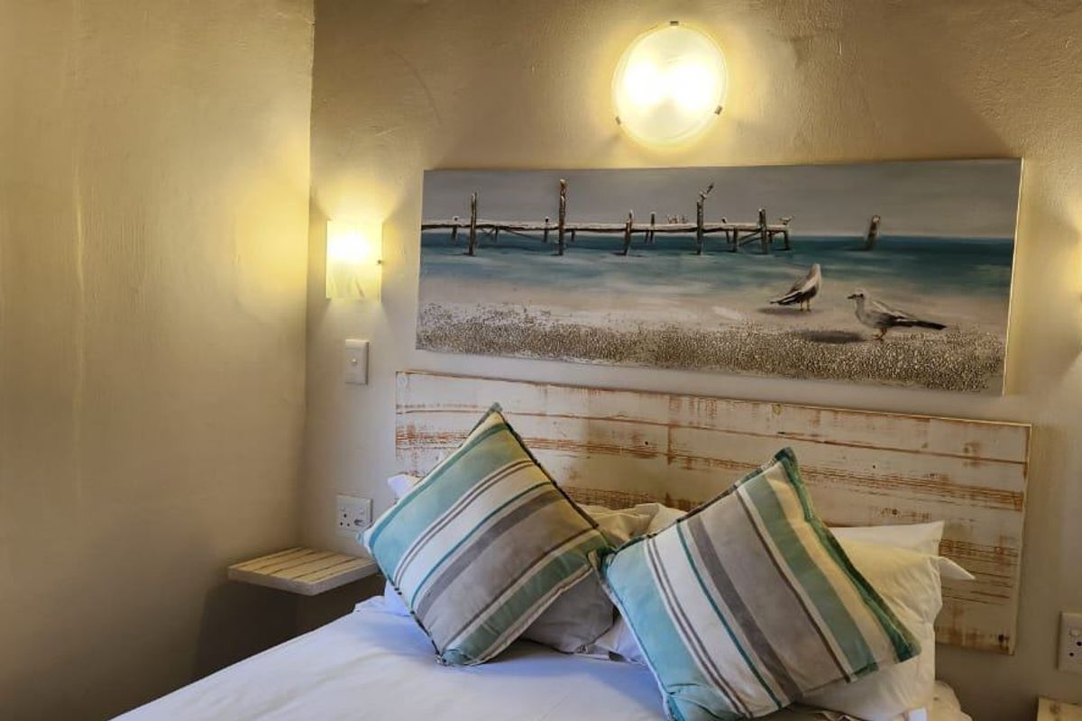 A cozy bedroom featuring wall-mounted lighting, venetian blinds, and integrated electrical points, providing a functional and comfortable sleeping space.