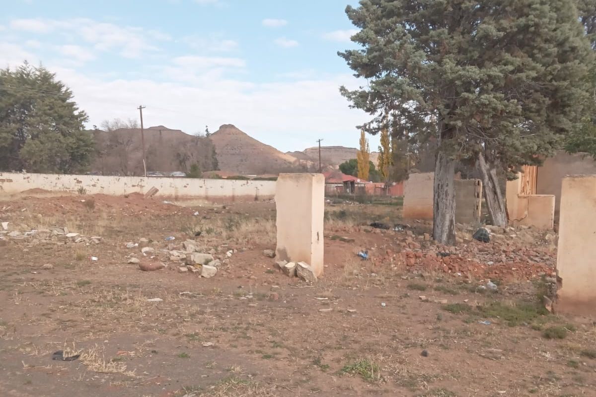 Vacant residential land featuring remnants of previous structures, mature trees, and a boundary wall, offering a blank canvas for new development.