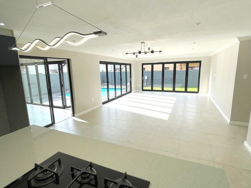 Spacious open-plan living and kitchen area featuring modern finishes, a built-in gas hob, and large stacker doors opening to the pool area.