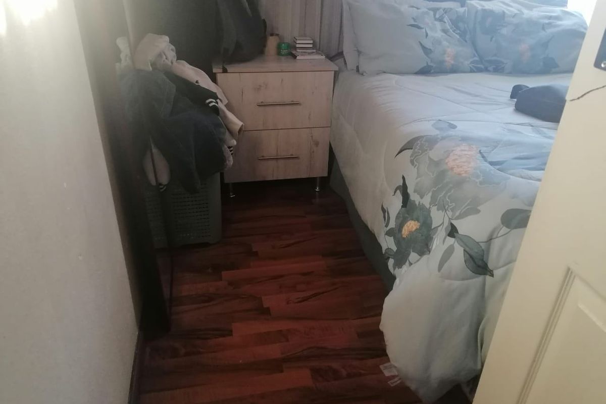 A bedroom featuring dark wood-look laminate flooring and a compact layout.