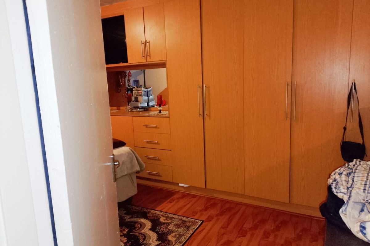 A bedroom featuring extensive built-in wooden cabinetry and warm-toned laminate flooring, providing ample storage space.