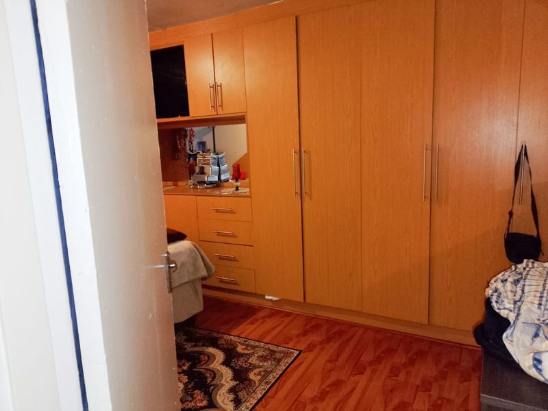 A bedroom featuring extensive built-in wooden cabinetry and warm-toned laminate flooring, providing ample storage space.