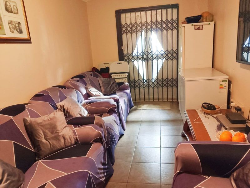 A living room area featuring tiled flooring and a secure metal gate leading to the exterior.