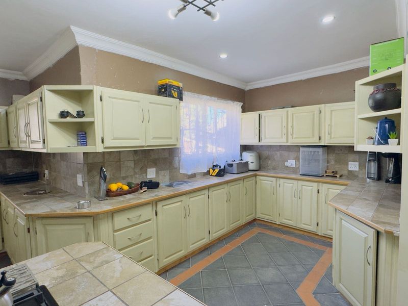 A functional kitchen featuring tiled countertops, backsplash, and flooring with ample built-in cabinetry and recessed lighting.