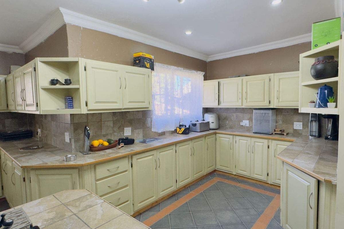 A functional kitchen featuring tiled countertops, backsplash, and flooring with ample built-in cabinetry and recessed lighting.