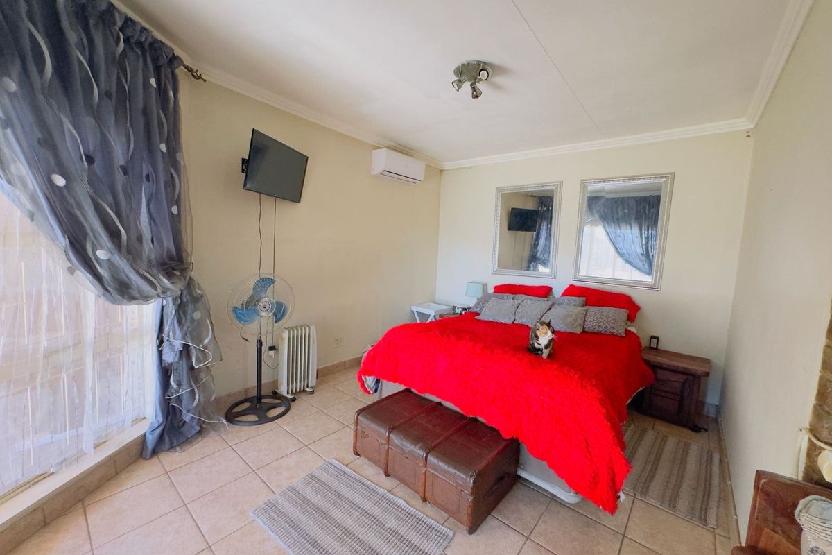 A bedroom featuring tiled flooring, an air conditioning unit, and wall-mounted television bracket.