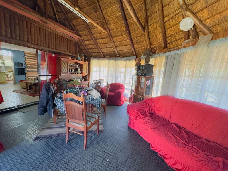 Spacious living area featuring a traditional thatched roof with exposed timber rafters and direct access to the kitchen through sliding glass doors.