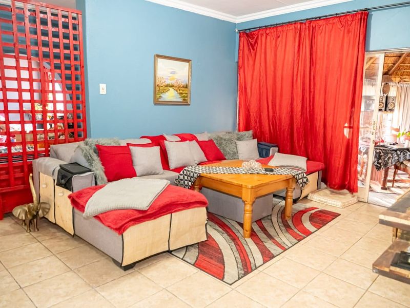 A living room area featuring tiled flooring and access to an adjoining patio space through a sliding door.