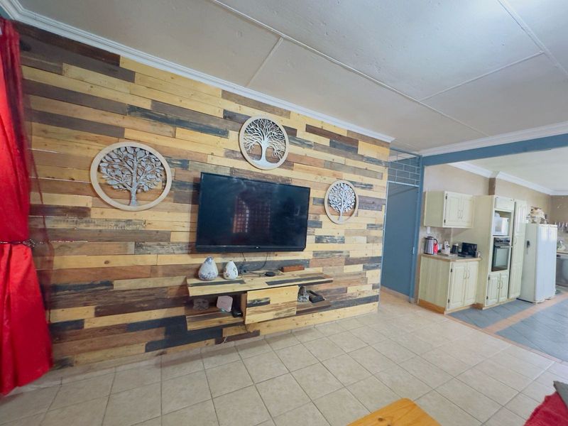 Open plan living area featuring a timber plank feature wall and an adjoining kitchen with built-in cabinetry and oven.