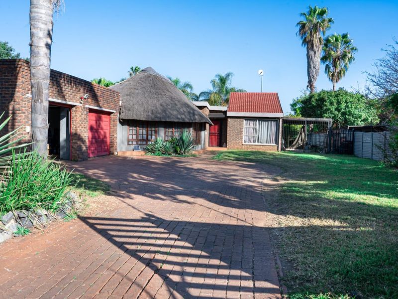 Front exterior view of a house featuring a brick driveway, a combination of thatch and tiled roofing, and a garage.