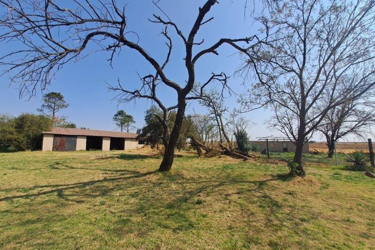 Expansive farm grounds featuring mature trees, open grass areas, and a detached outbuilding with a corrugated metal roof.