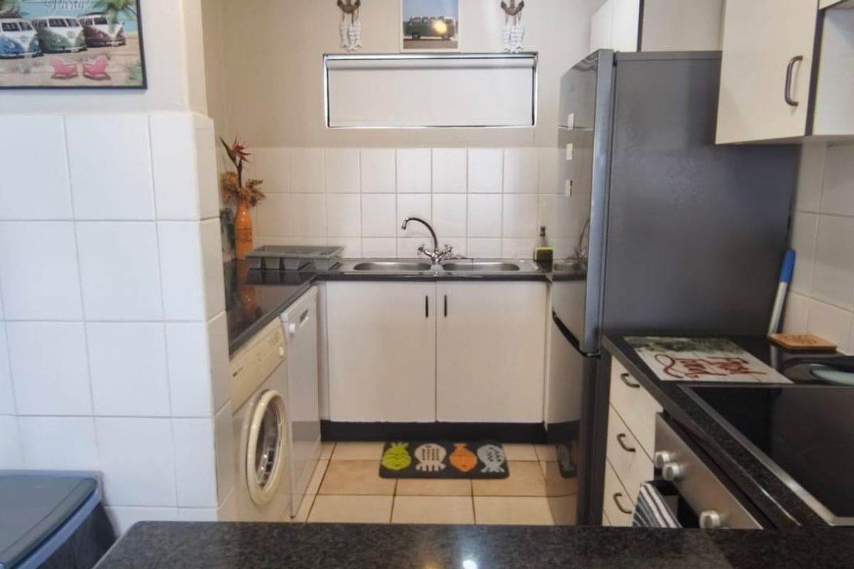 Compact kitchen featuring granite countertops, tiled backsplash, built-in cabinetry, and integrated electric cooking appliances.
