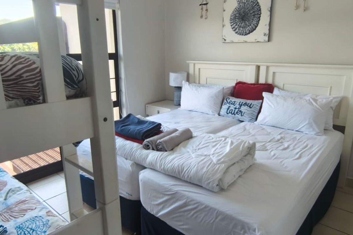 A functional bedroom featuring tiled flooring and access to an outdoor area via a sliding door, providing natural light and ventilation.