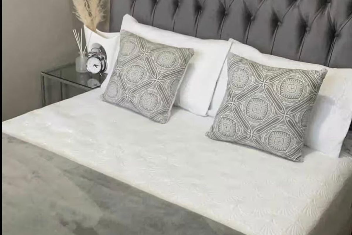 A well-presented bedroom featuring a tufted grey headboard and neutral finishes, creating a comfortable and inviting sleeping space.