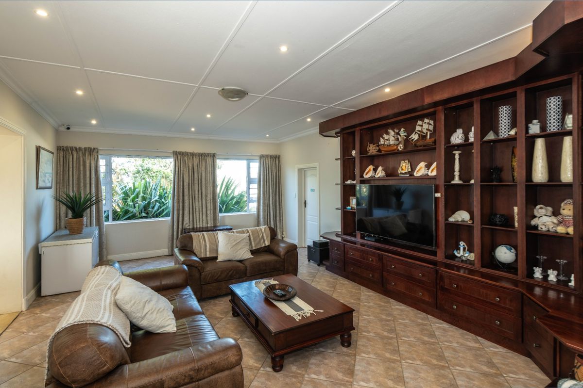 Spacious living room featuring extensive built-in wooden cabinetry, tiled flooring, and recessed lighting, offering a warm and functional space for relaxation.