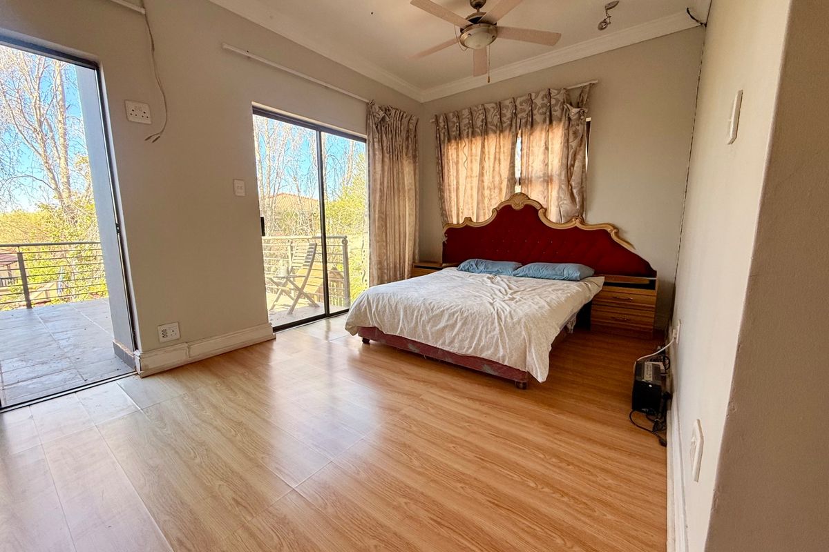 A bedroom featuring laminate flooring, a ceiling fan, and direct access to an outdoor balcony through sliding glass doors.