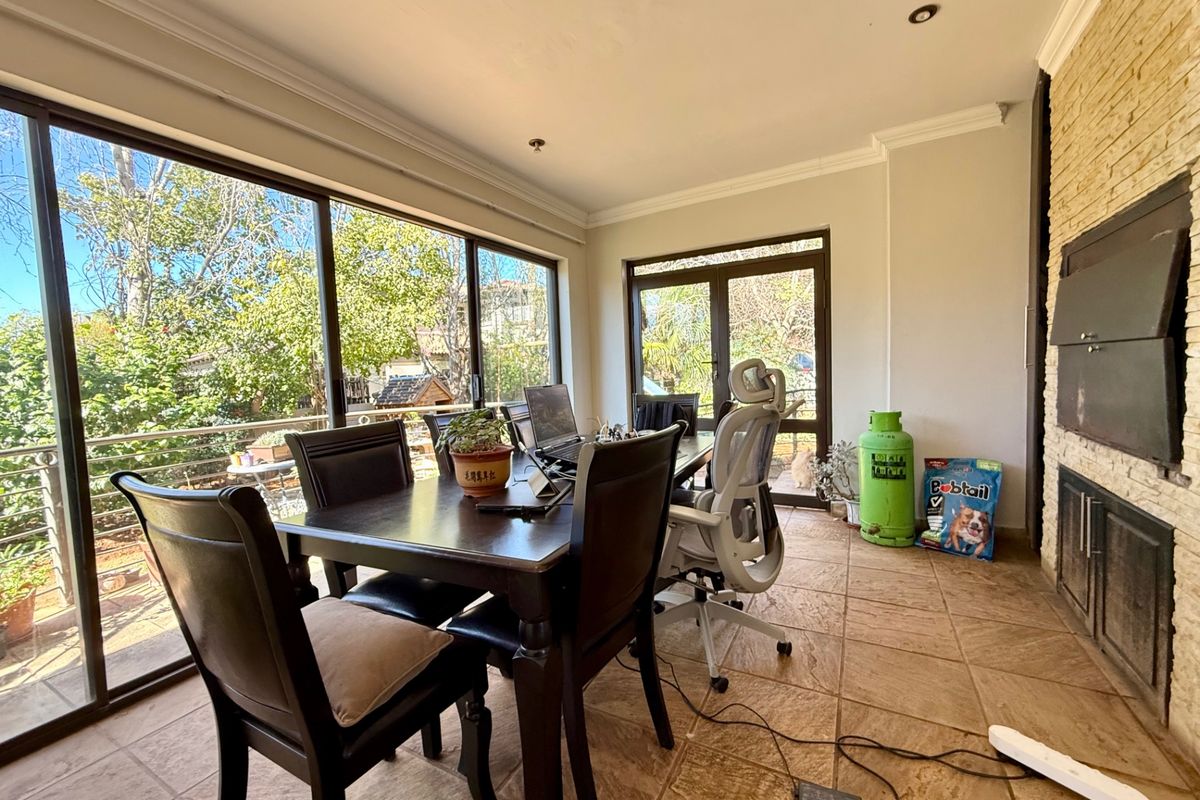 A bright living area featuring large sliding glass doors, tiled flooring, and a prominent stone-clad fireplace, offering direct access to the outdoor space.