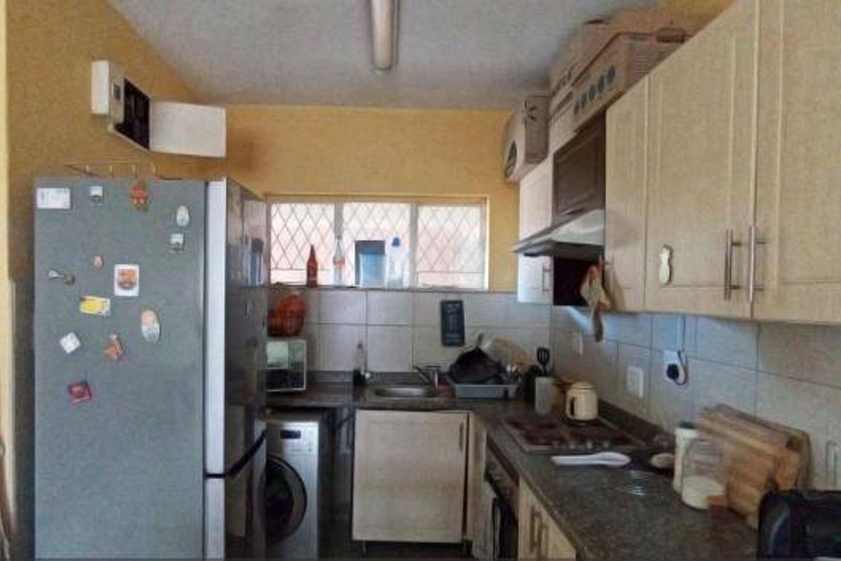 A functional kitchen featuring built-in cabinetry, a tiled backsplash, and integrated appliances, showing signs of wear and ceiling water damage.