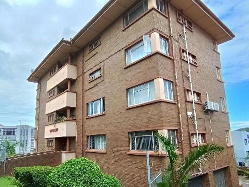 A multi-story brick apartment building featuring balconies, security window bars, and external air conditioning units, showcasing a classic residential architectural style.