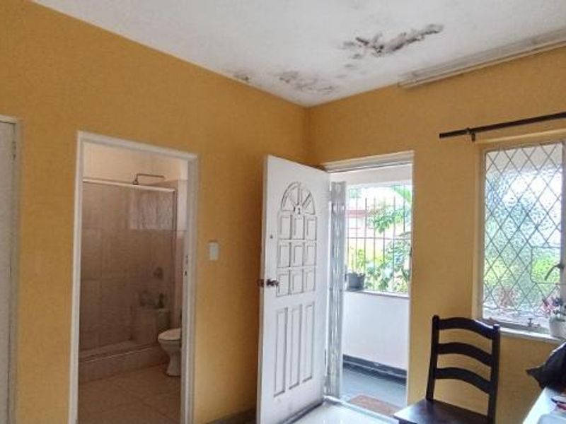Bedroom featuring yellow walls, security bars on windows, and an attached bathroom. The ceiling shows visible signs of water damage.