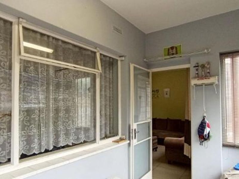 Enclosed balcony or sunroom featuring large windows, tiled flooring, and an integrated air conditioning unit, providing a bright and versatile transition space.