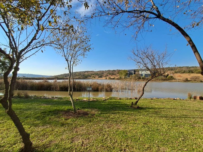 A scenic view of a tranquil lake surrounded by natural vegetation and landscaped lawn, offering a peaceful outdoor setting.