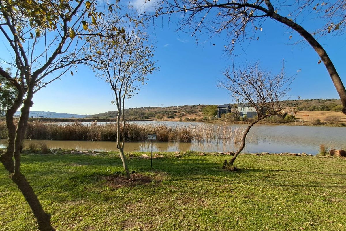 A scenic view of a tranquil lake surrounded by natural vegetation and landscaped lawn, offering a peaceful outdoor setting.