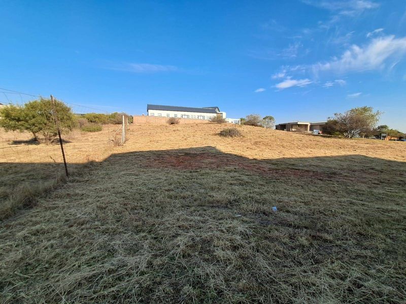 A view of the sloped, undeveloped residential land featuring wire fencing and surrounding neighborhood properties in the distance.