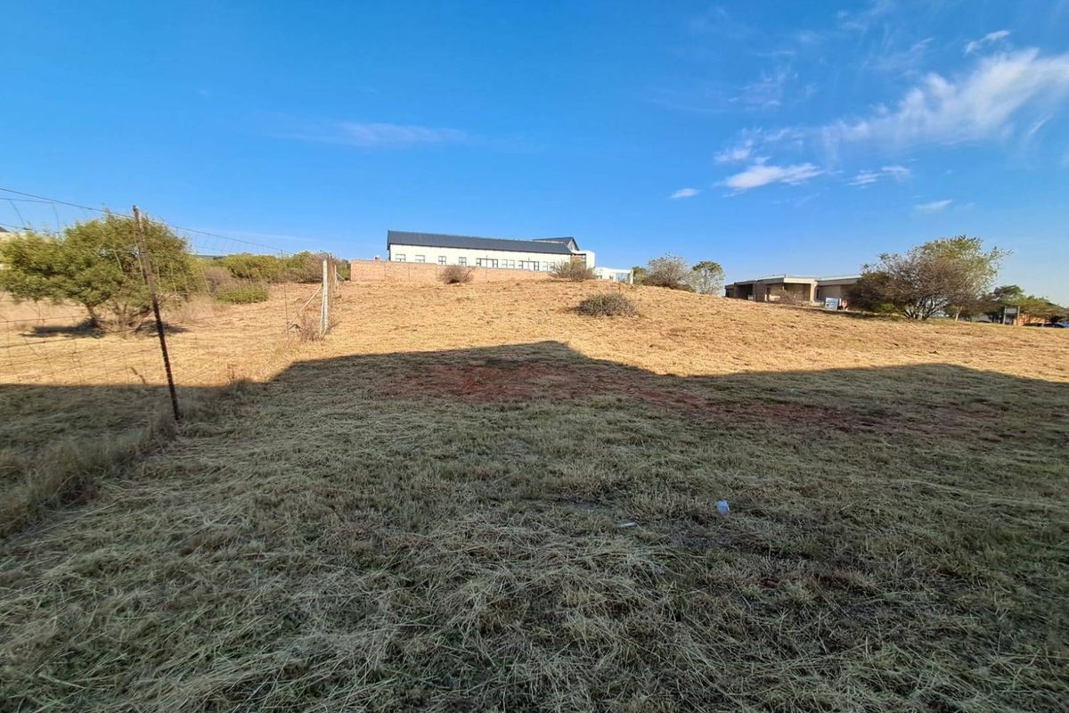 A view of the sloped, undeveloped residential land featuring wire fencing and surrounding neighborhood properties in the distance.