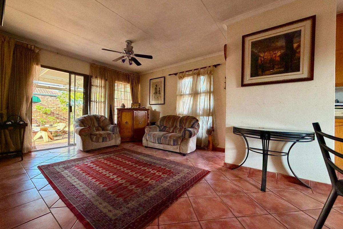 A living room featuring tiled flooring, a ceiling fan, and sliding glass doors providing access to an outdoor patio area.