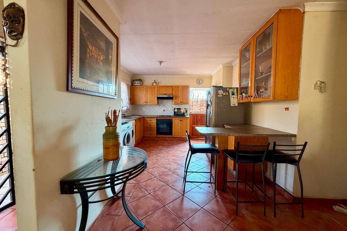A functional kitchen featuring wooden cabinetry, a built-in oven with extractor fan, tiled flooring, and a convenient breakfast bar for casual dining.