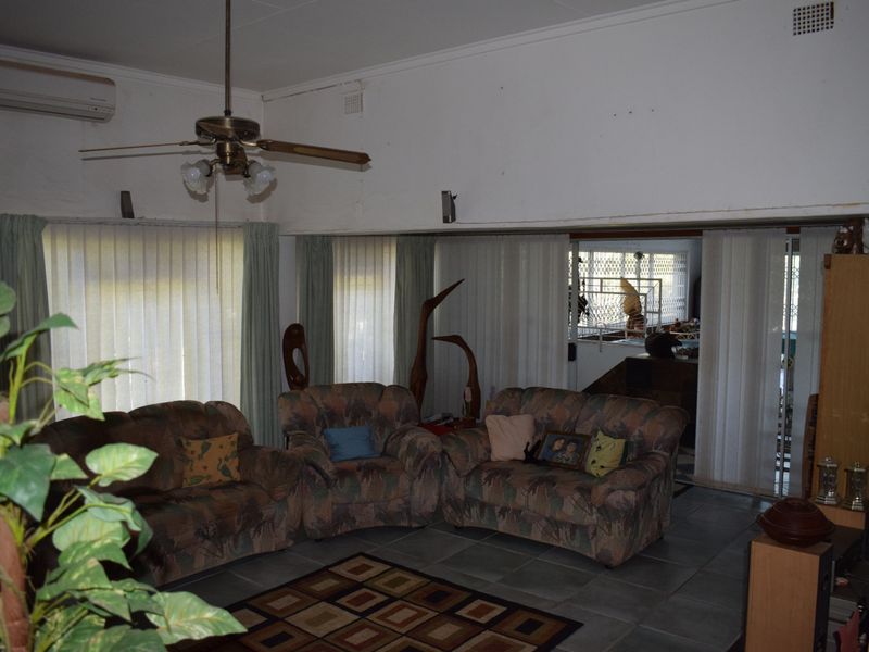 Spacious living room featuring tiled flooring, a ceiling fan, and split-system air conditioning, with sliding doors providing access to an adjacent area.